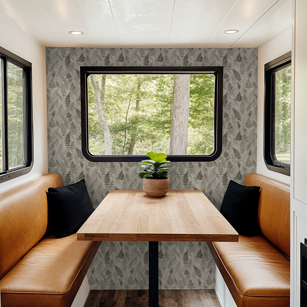 Botanical fern wallpaper in cozy dining nook with leather seating and wood table.