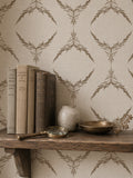 Botanical taupe on cream wallpaper with books and decor on a wooden shelf.