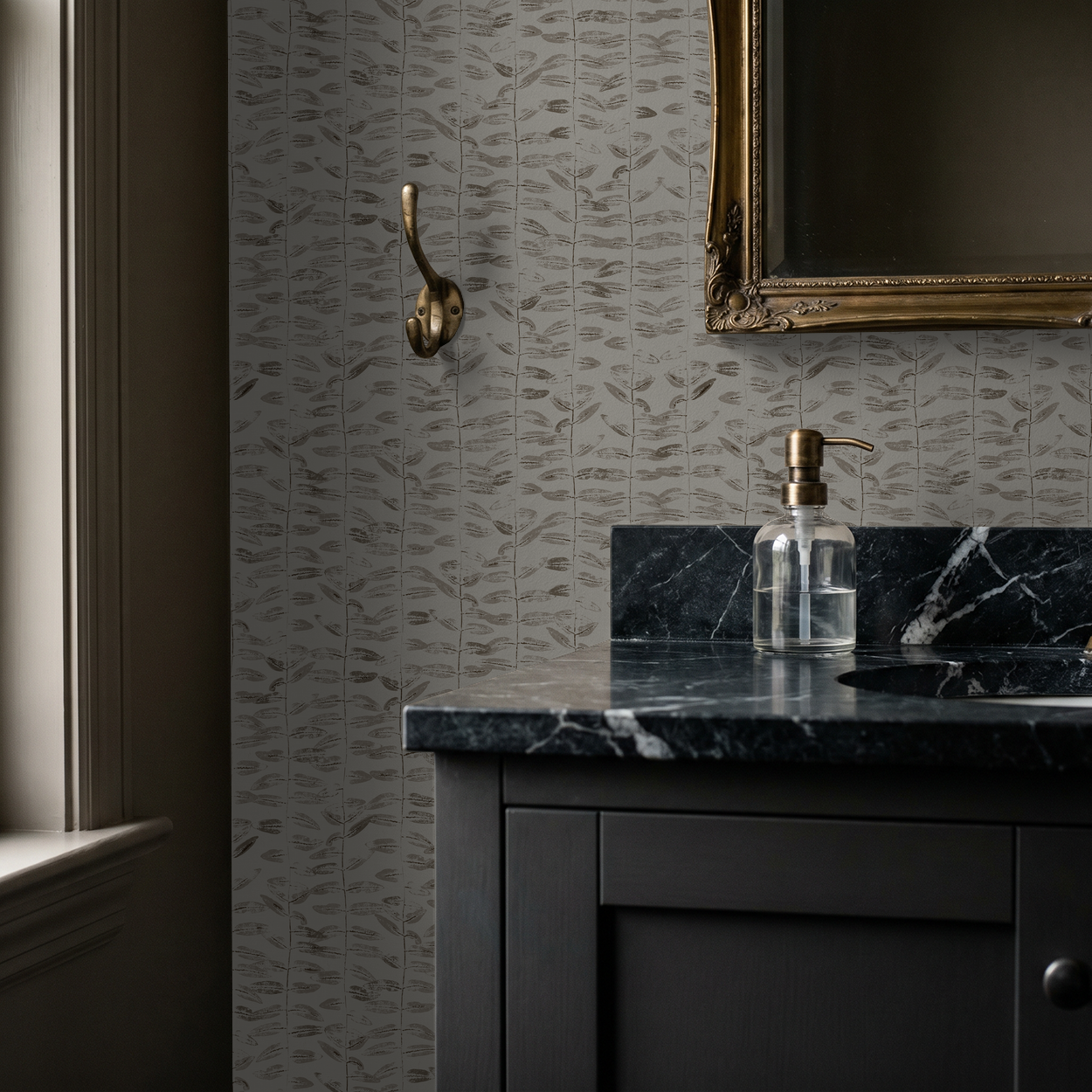 Botanical taupe wallpaper in elegant bathroom with black marble countertop and gold mirror.