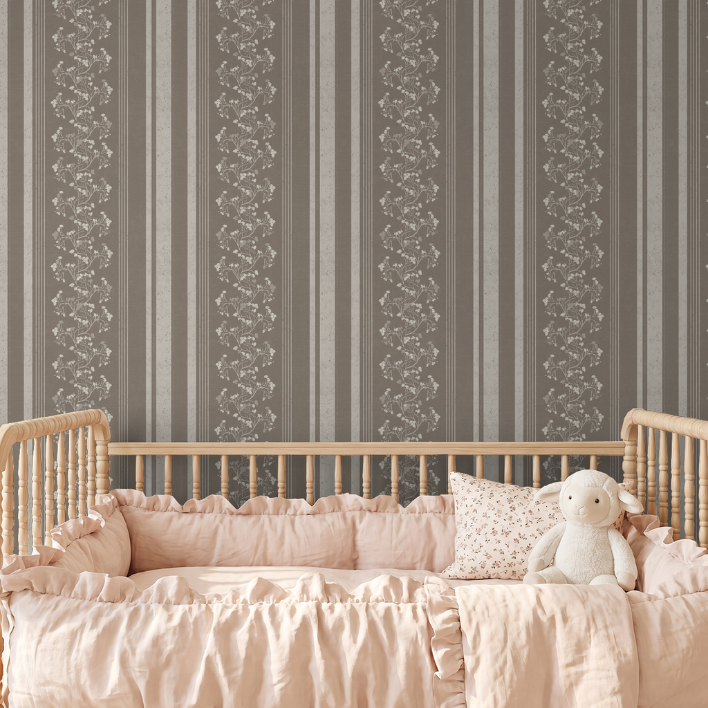 Brown floral stripe wallpaper in nursery with wooden crib and pink bedding.