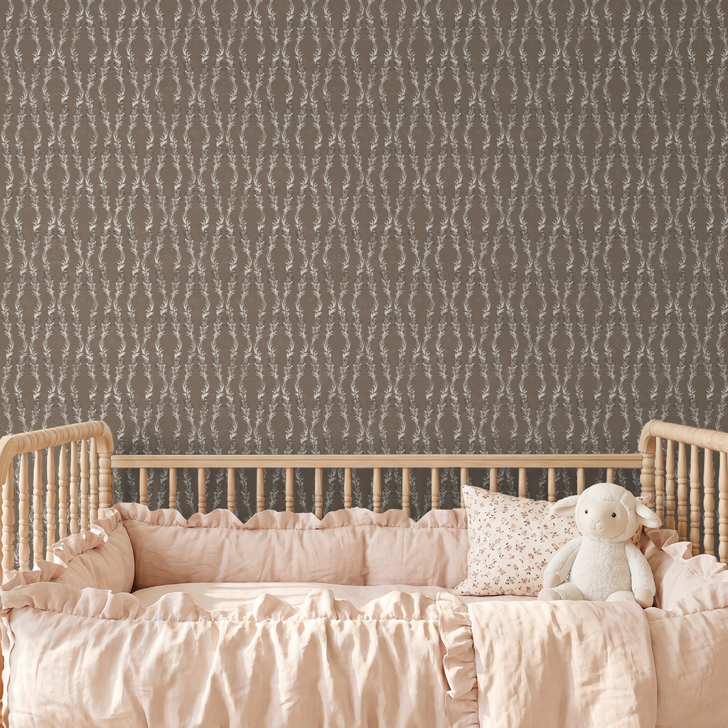 Brown floral vine wallpaper in nursery with wooden crib and pink bedding.