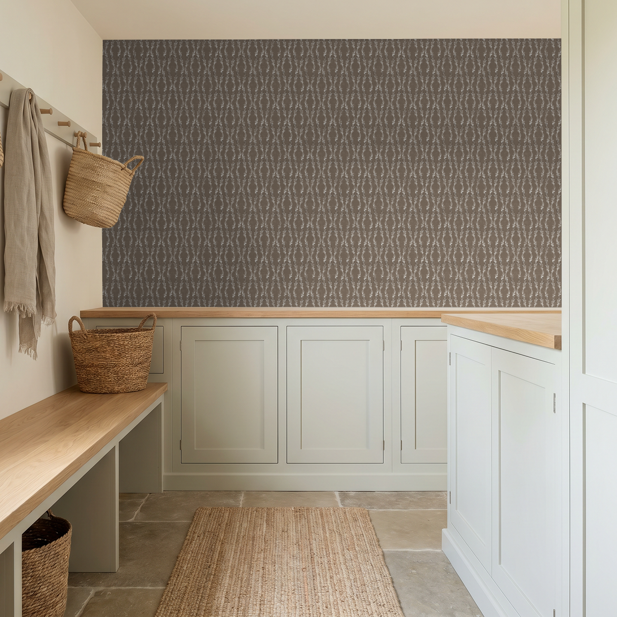 Brown floral vine wallpaper in rustic mudroom with beige cabinets and baskets.