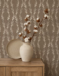 Brown floral vine wallpaper in rustic room with vase and wooden cabinet.