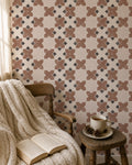 Burnt orange geometric tile wallpaper in cozy reading nook with chair and blanket.