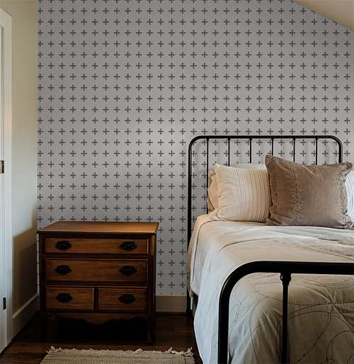 Charcoal cross pattern wallpaper in cozy bedroom with metal bed frame.