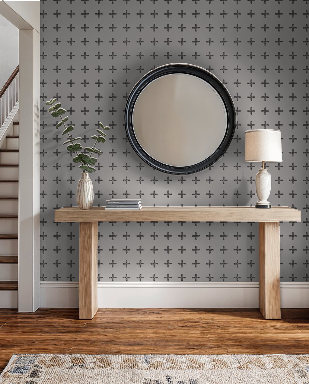 Modern room with charcoal cross pattern wallpaper, wood console, and round mirror.