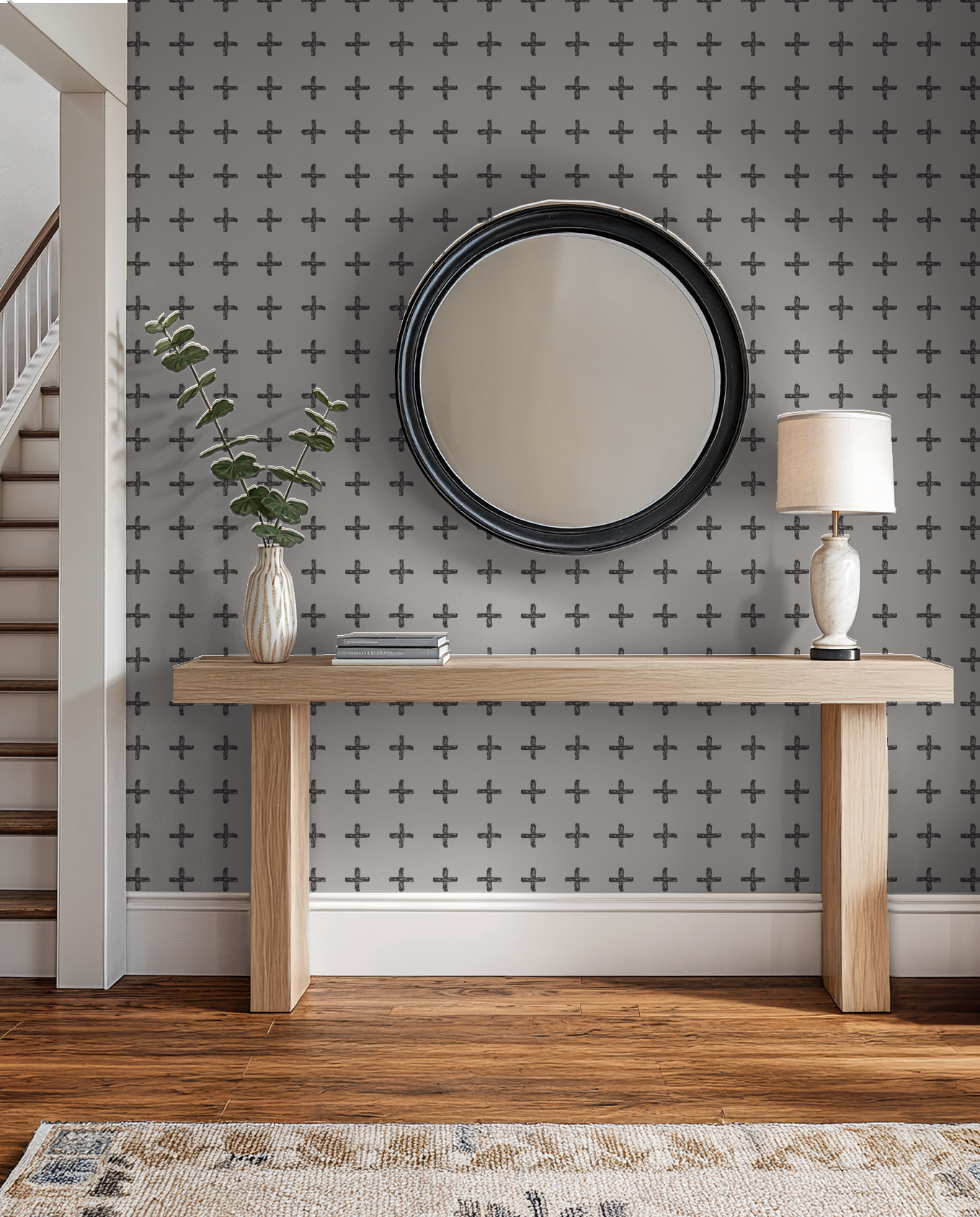 Modern room with charcoal cross pattern wallpaper, wood console, and round mirror.
