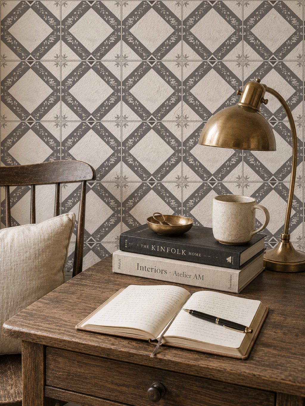 Charcoal gray botanical trellis wallpaper in cozy study with wooden desk and lamp.