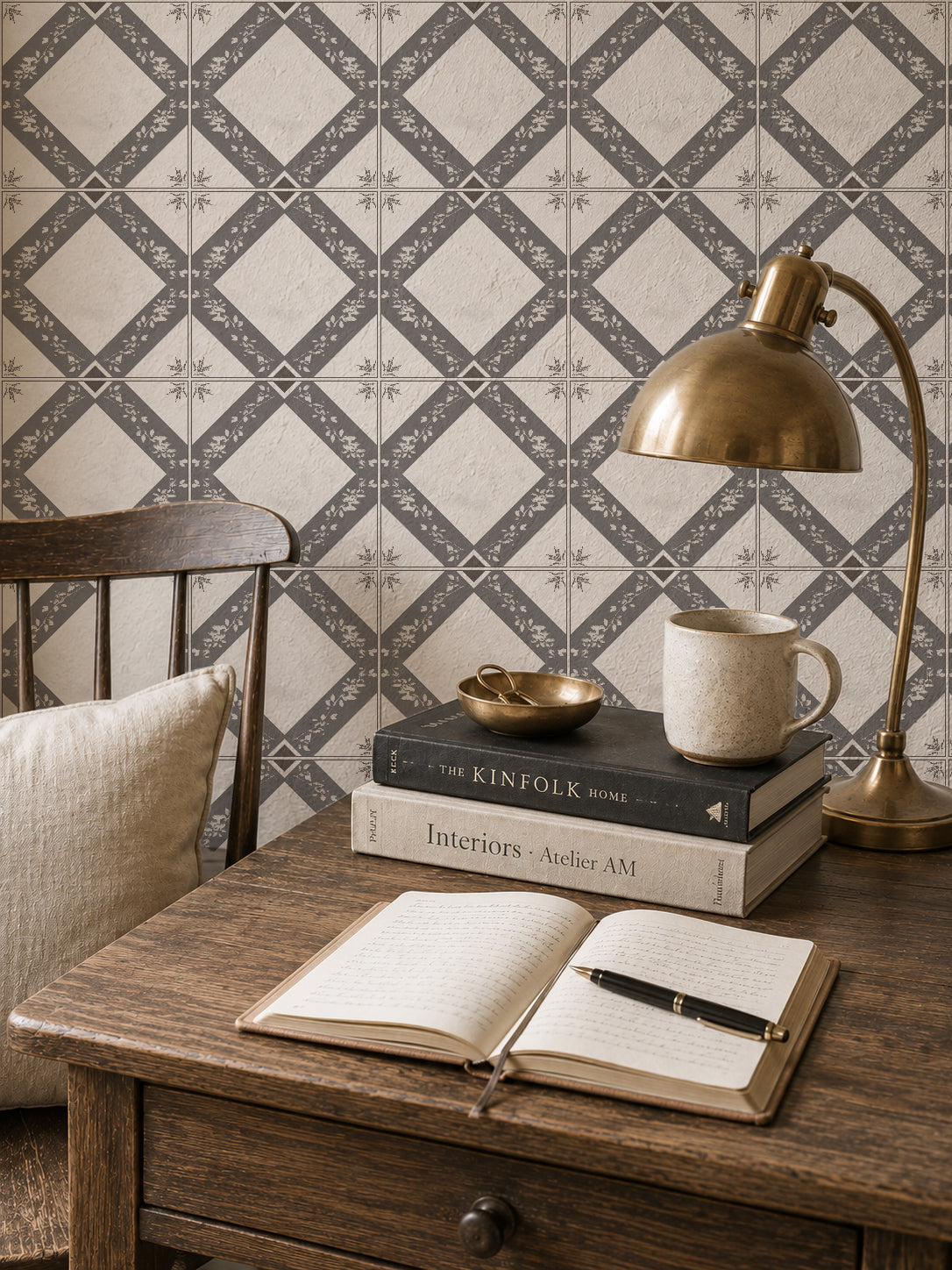 Charcoal gray botanical trellis wallpaper in cozy study with wooden desk and lamp.