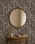 Chevron herringbone wallpaper in charcoal and cream with round mirror and wooden table.