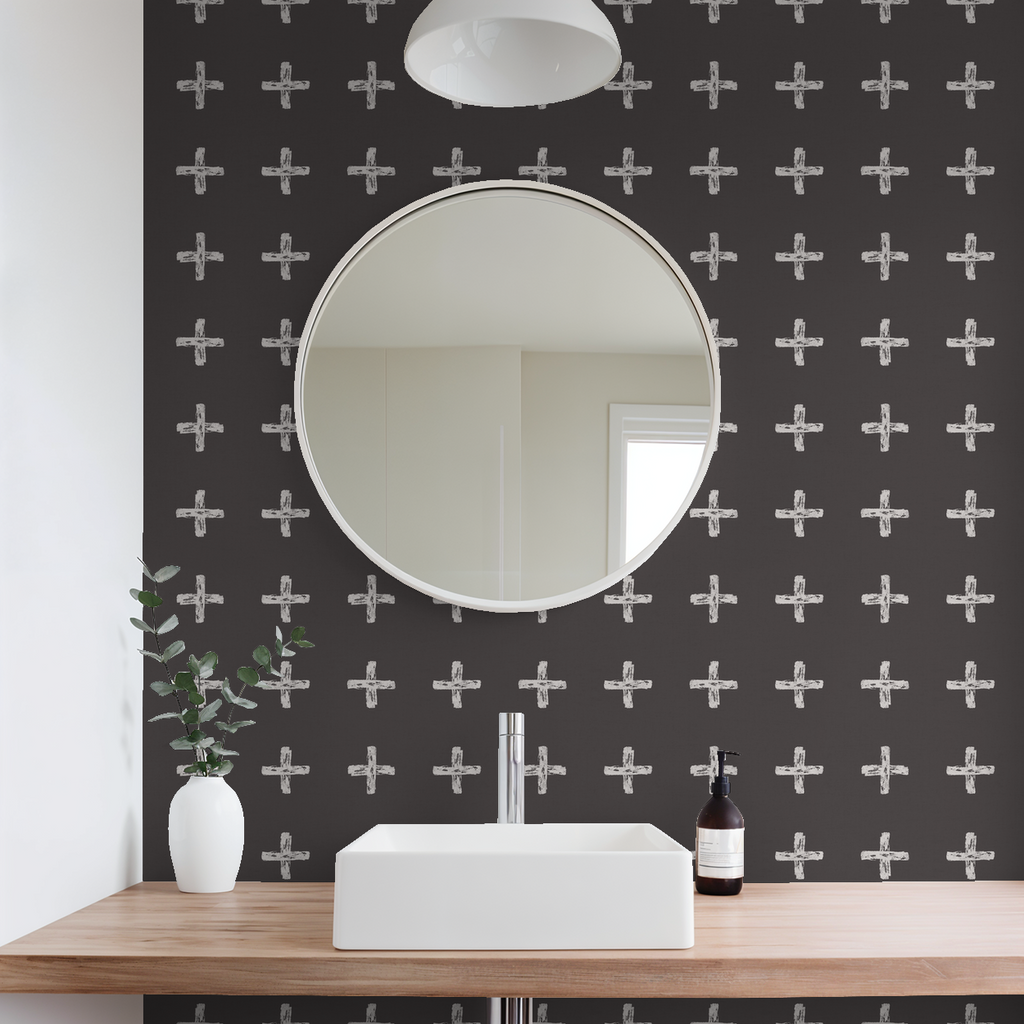 Modern bathroom with cream cross pattern wallpaper on charcoal, round mirror, and white sink.