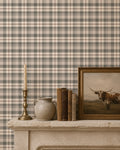 Cream and green plaid wallpaper in a rustic room with books and a candle on a mantel.