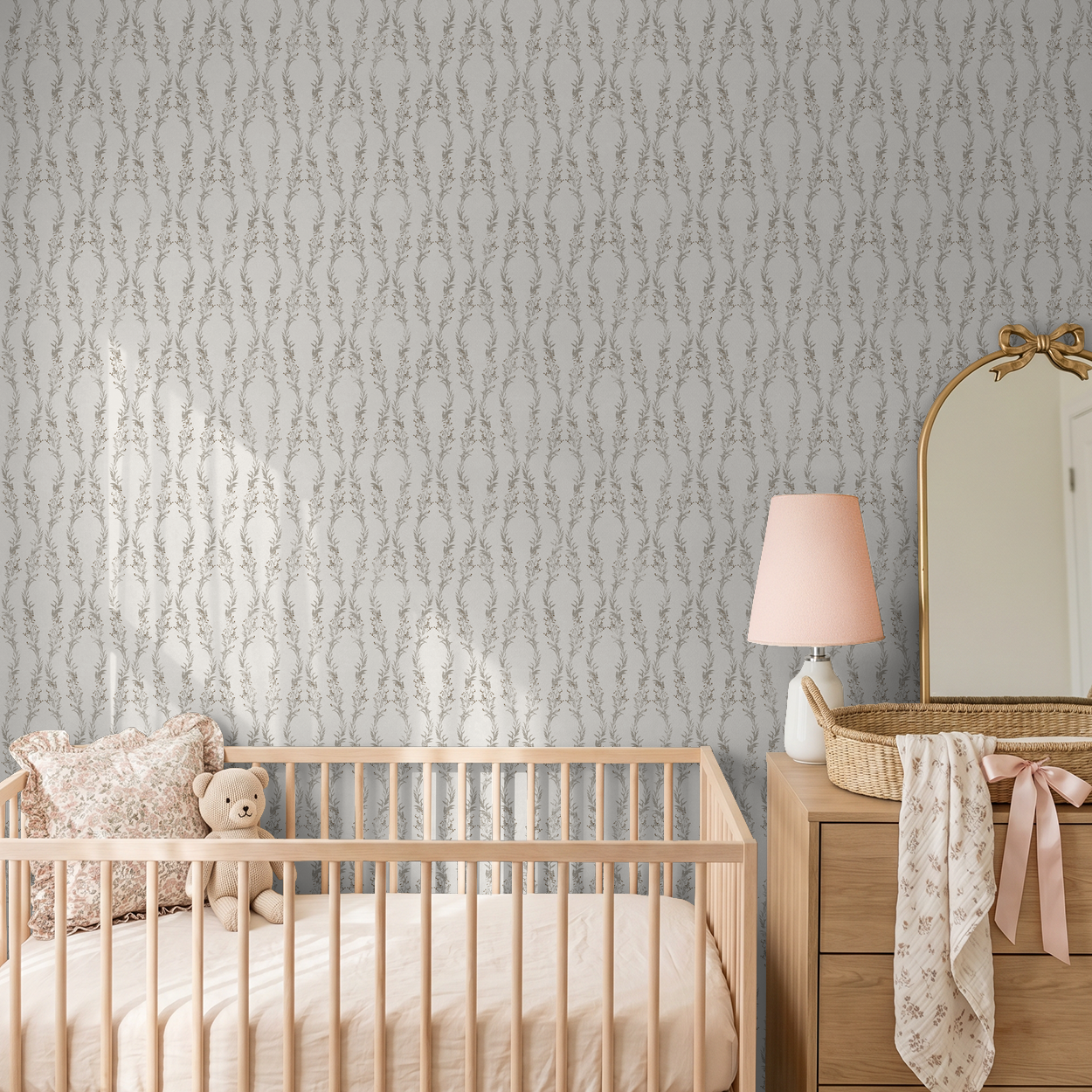 Nursery with floral gray wallpaper, wooden crib, and dresser with mirror.