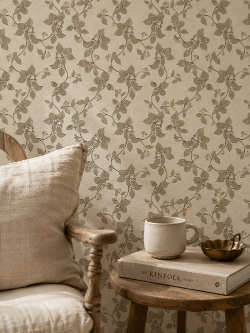 Floral vine sage wallpaper in cozy rustic setting with wooden chair and table.