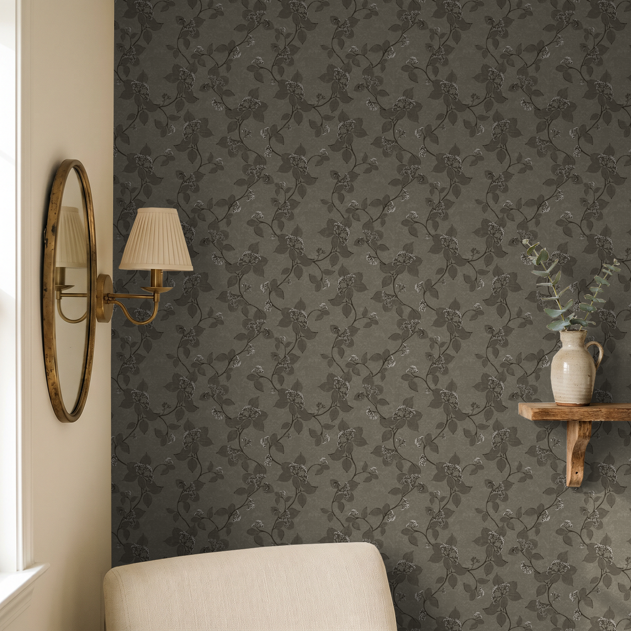 Floral vine patterned wallpaper in earthy tones in a cozy room with a mirror and lamp.