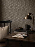 Floral wallpaper with slate backdrop in cozy study setting with books and lamp.