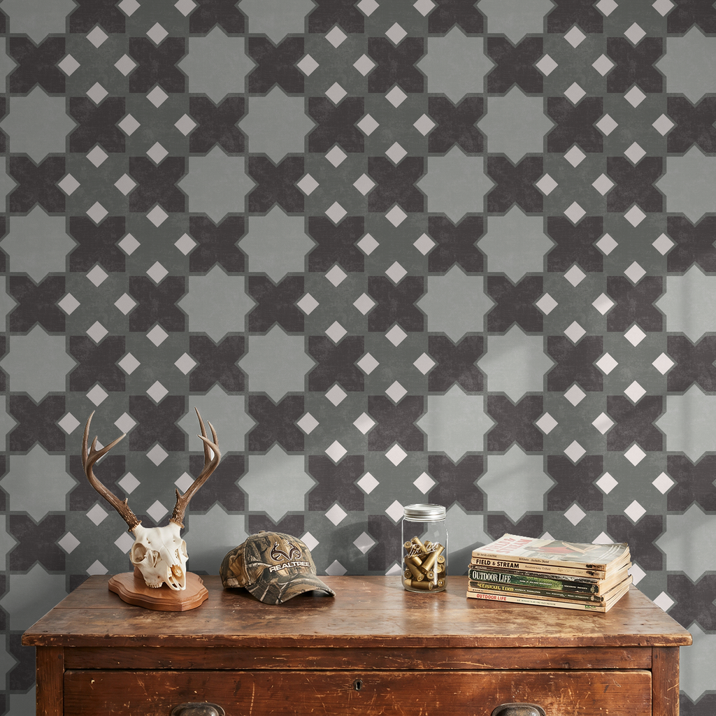 Geometric tile green wallpaper in rustic room with antler decor and books.