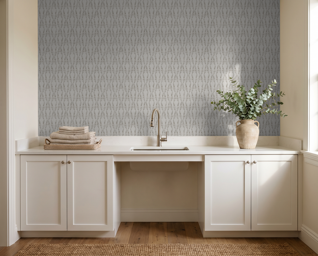 Gray botanical wallpaper in elegant laundry room with white cabinets and vase.