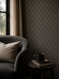 Slate wallpaper with delicate vine pattern in cozy living room with dark armchair.