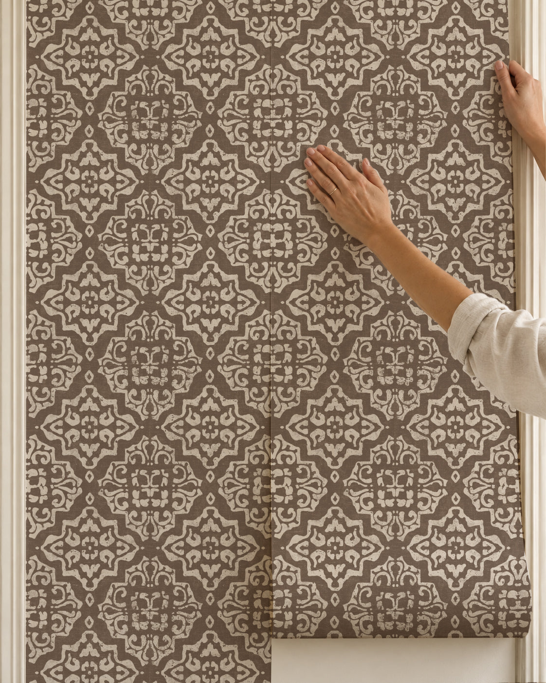 Mocha and cream damask wallpaper with intricate geometric pattern being applied