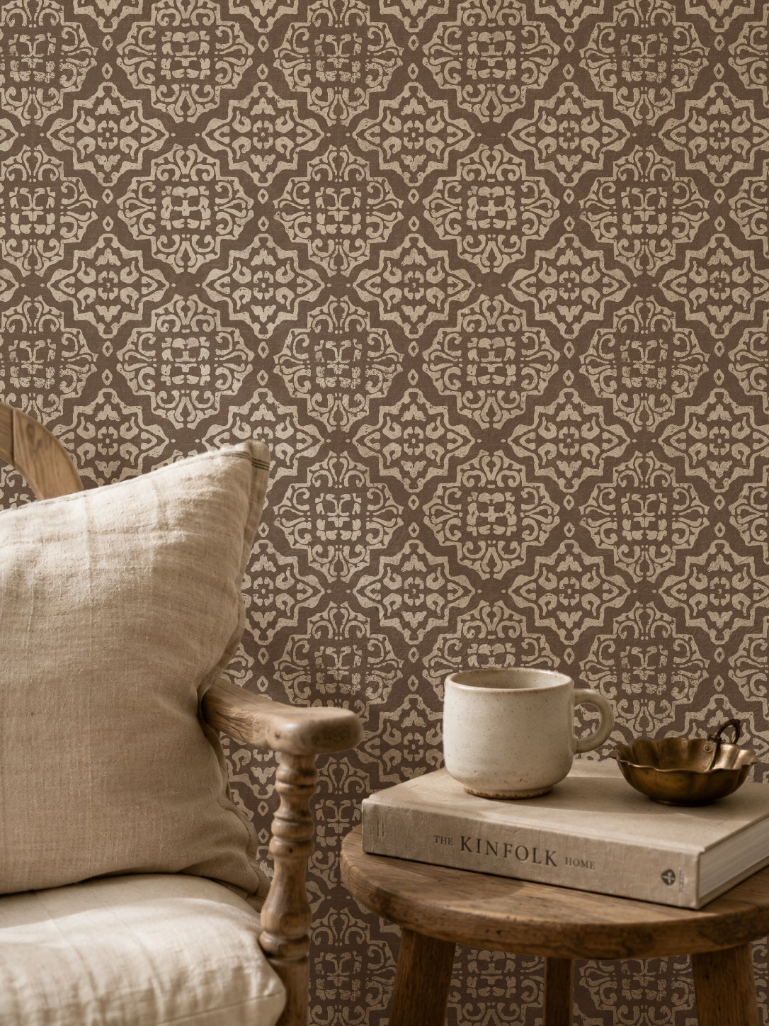 Mocha and cream damask wallpaper in cozy sitting area with chair and books.