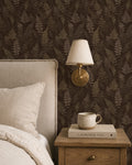 Moody espresso fern wallpaper in cozy bedroom with lamp and nightstand.
