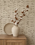 Olive branch linen wallpaper with botanical pattern in neutral tones behind a wooden cabinet with a vase.