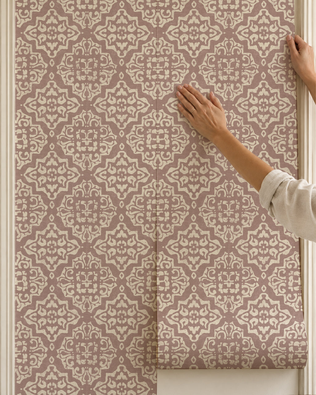 Elegant rosewood damask wallpaper with intricate cream motifs being installed.