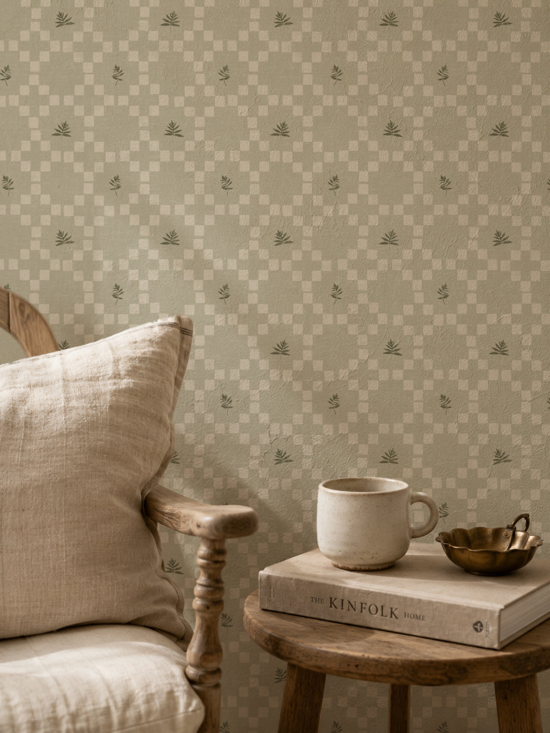 Sage botanical lattice wallpaper in cozy living room with wooden chair and table.