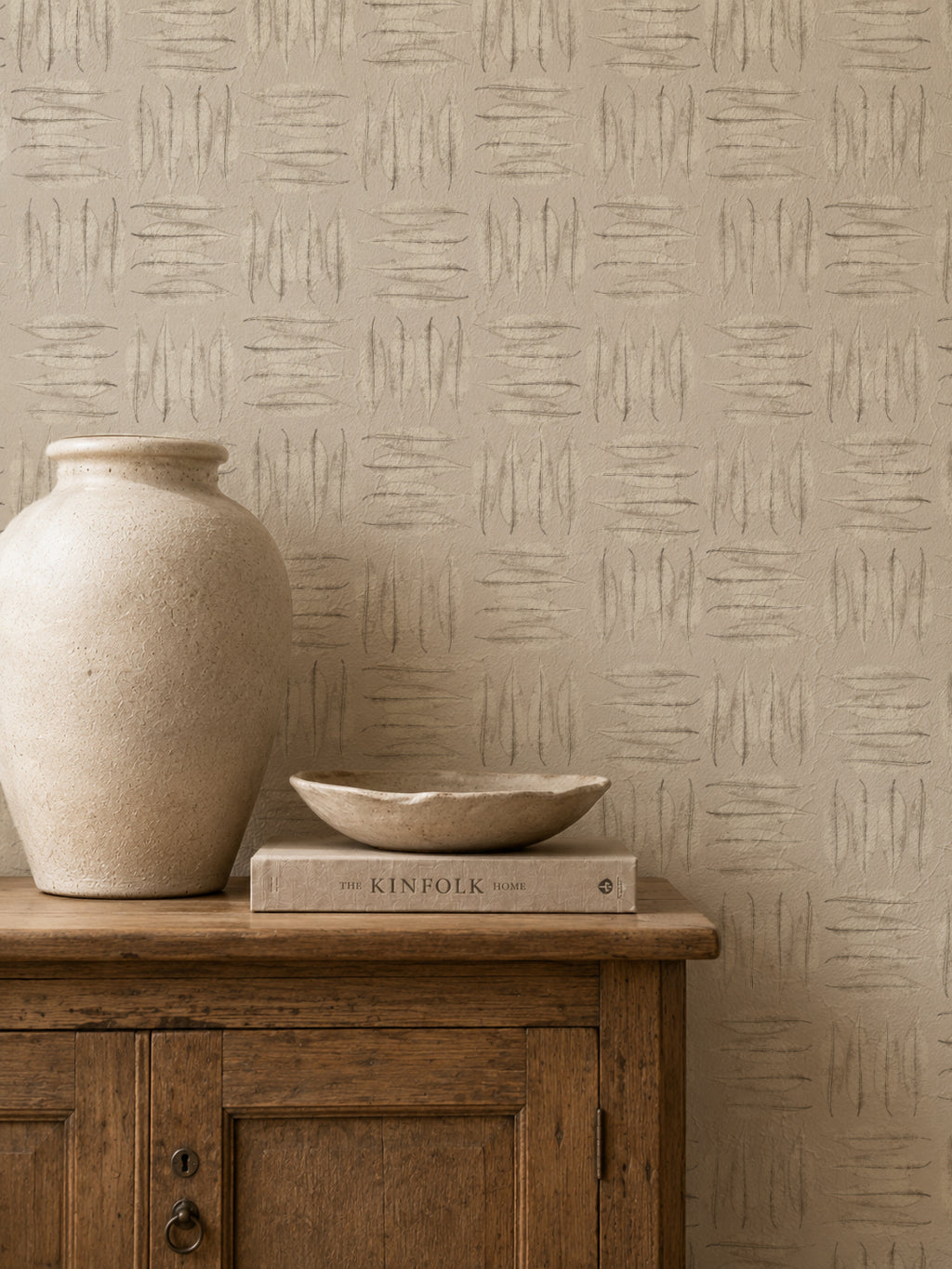 Stone leaf patterned wallpaper in rustic room with wooden cabinet and vase.
