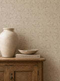 Stone leaf patterned wallpaper in rustic room with wooden cabinet and vase.