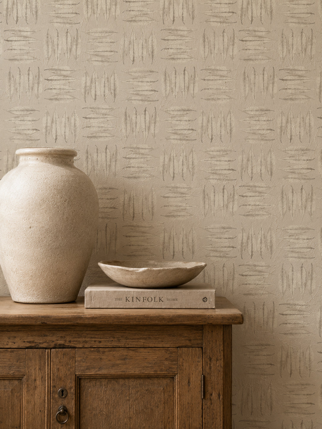 Stone leaf patterned wallpaper in rustic room with wooden cabinet and vase.