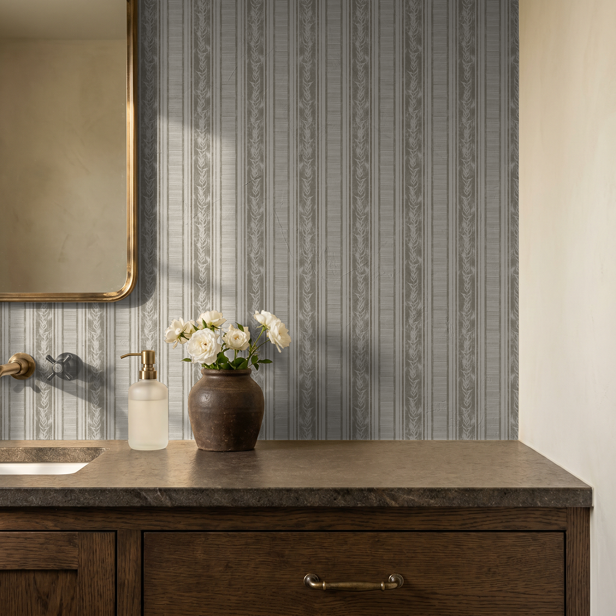 Taupe botanical stripe wallpaper in elegant bathroom with wood vanity and flowers.