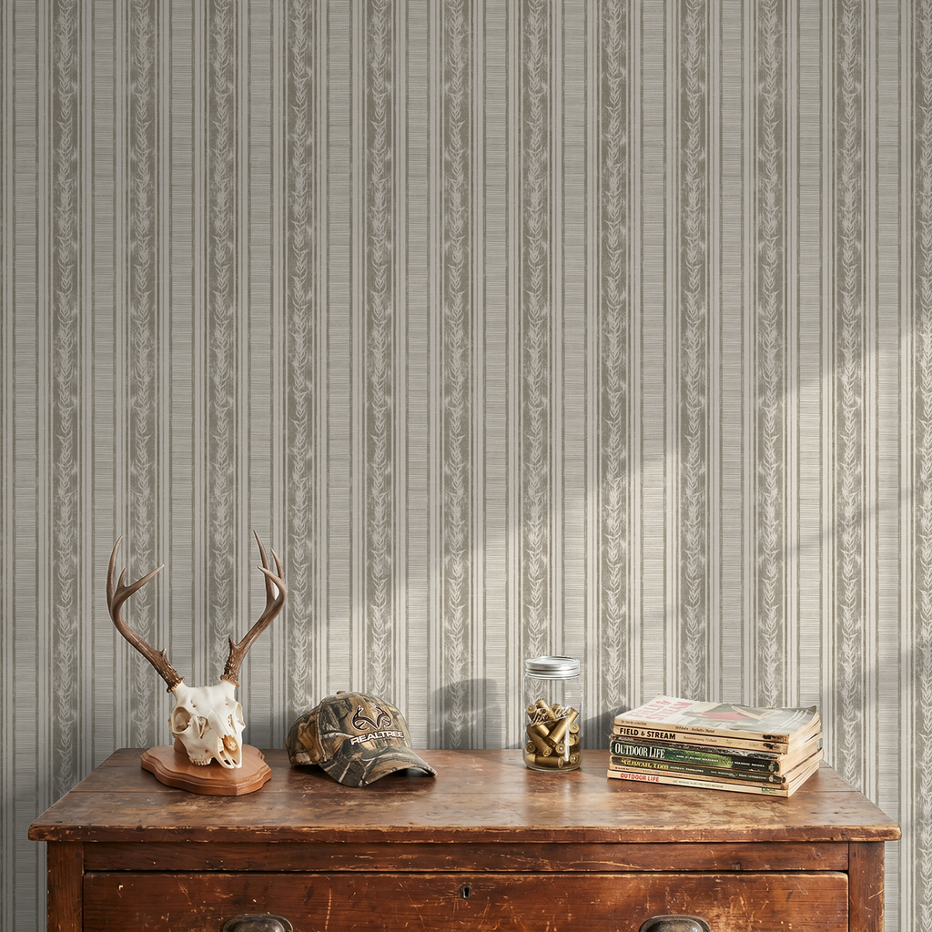 Taupe botanical stripe wallpaper with leaf motifs in rustic room setting.