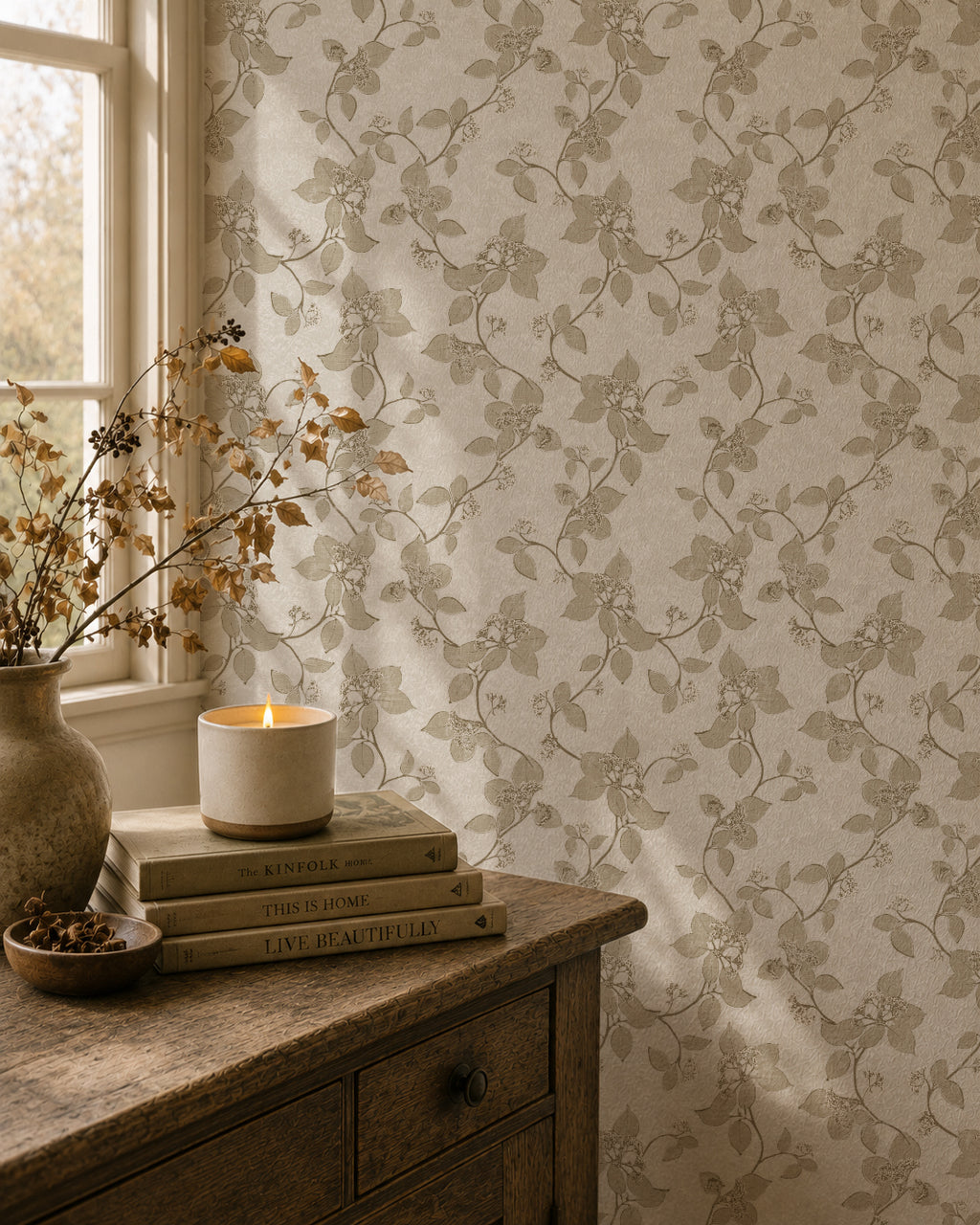 Taupe floral vine wallpaper in cozy room with candle and books.