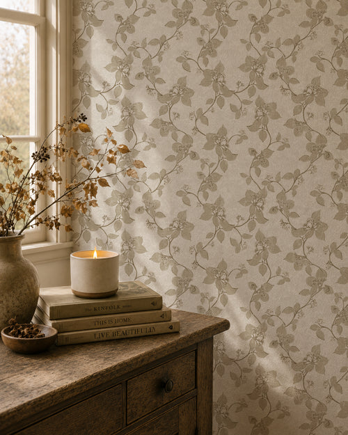 Taupe floral vine wallpaper in cozy room with candle and books.