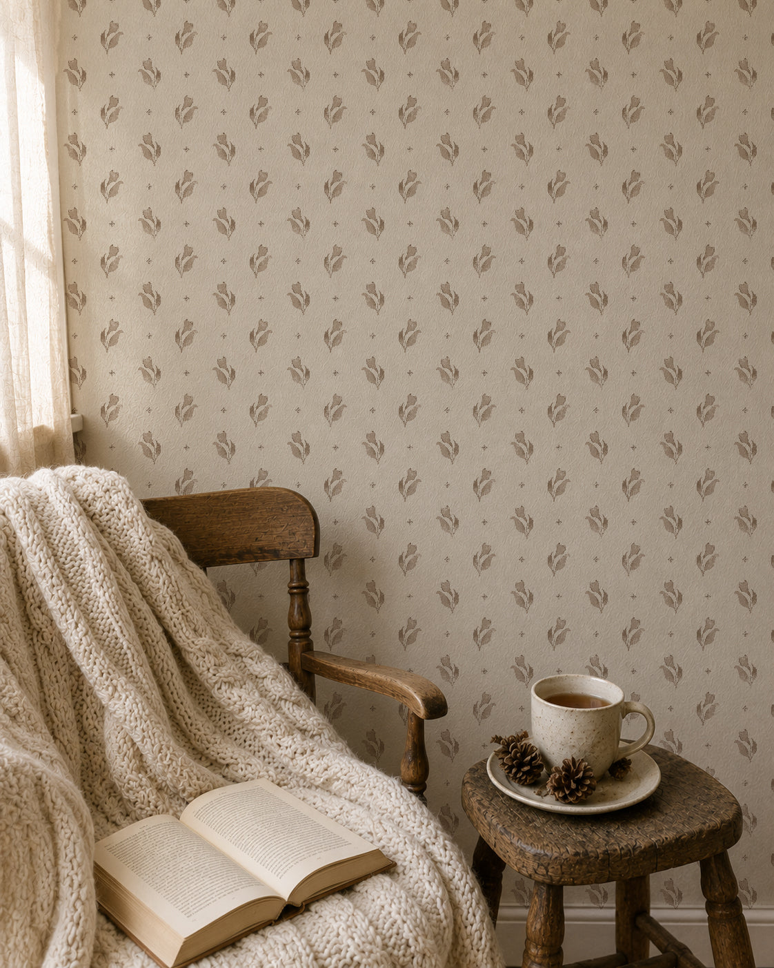 Taupe floral wallpaper in cozy room with chair, blanket, book, and coffee.