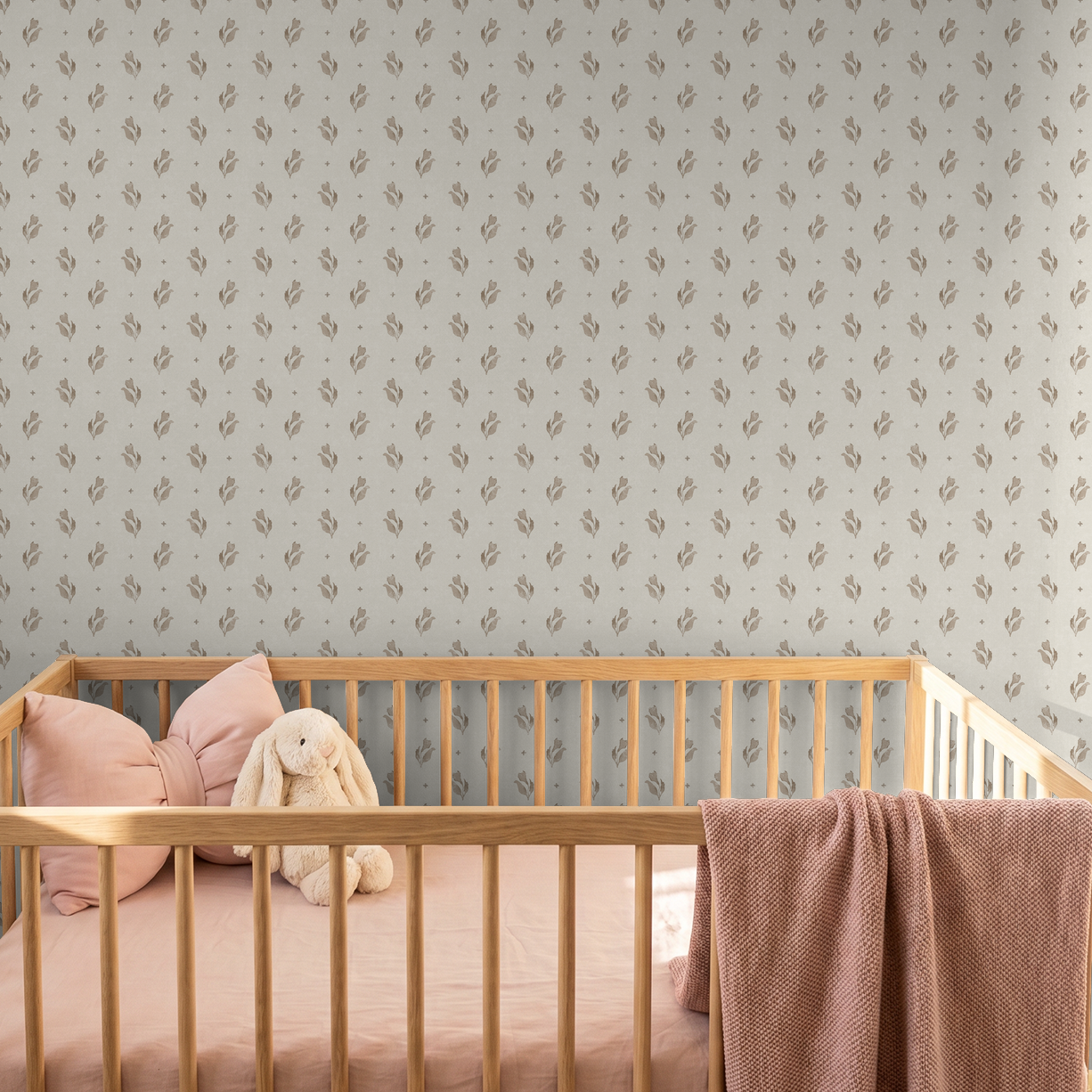 Taupe floral wallpaper in nursery with wooden crib and pink bedding.