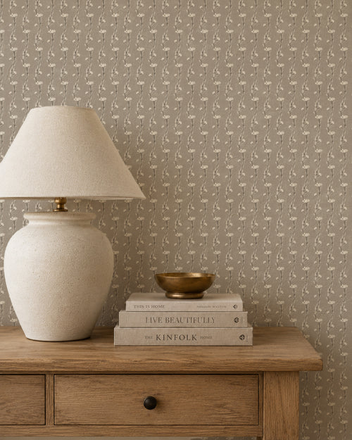 Taupe wallpaper with vine pattern in cozy room with wooden table and lamp.