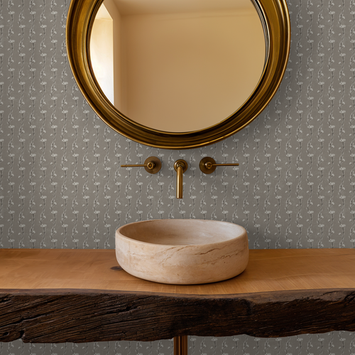 Taupe vine wallpaper with round mirror and rustic sink in bathroom.