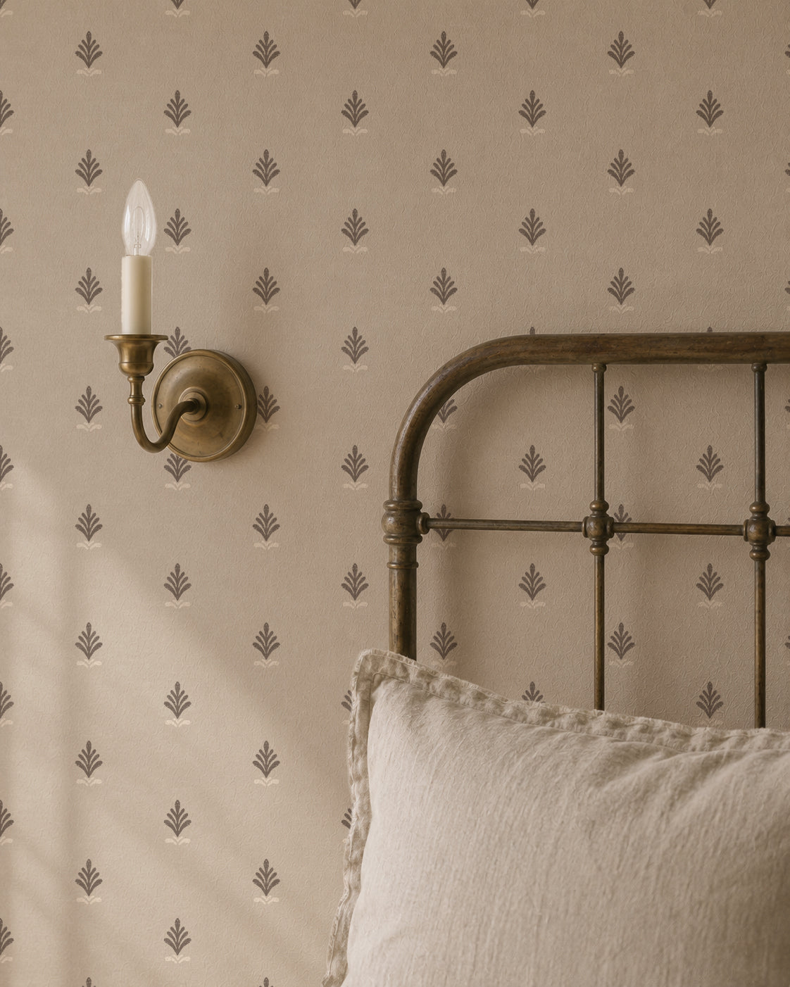 Vintage block print wallpaper in taupe with ornate motifs, styled in a classic bedroom setting.