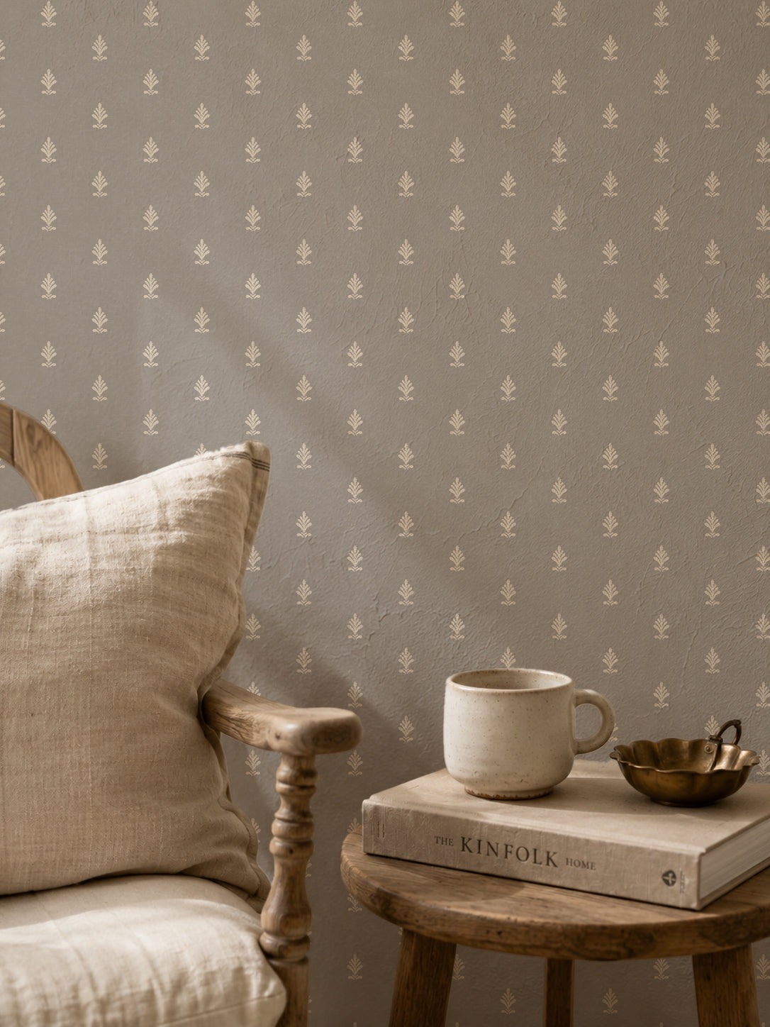 Vintage block print wallpaper with delicate motifs in a cozy setting with chair and books.