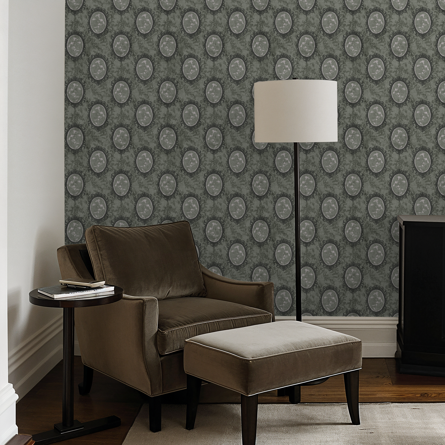 Vintage floral cameo wallpaper in taupe and charcoal in cozy living room with armchair and lamp.