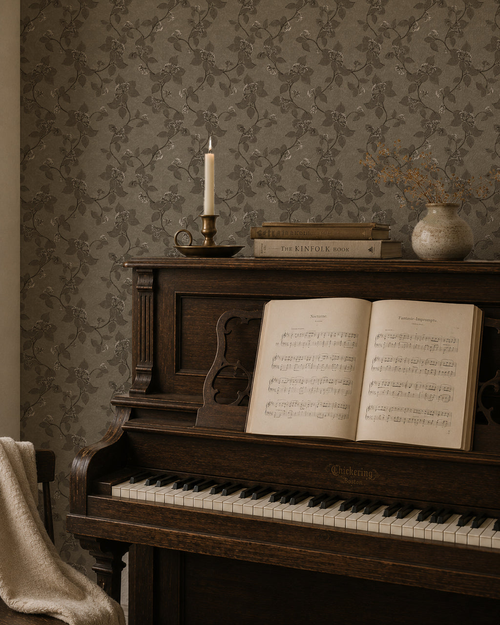 Vintage floral vine wallpaper in earth tones behind a dark wood piano with sheet music.